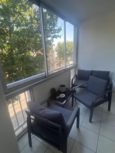 a living room with two chairs and a table and windows at Appartement in Valence