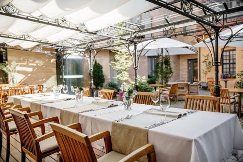 uma mesa com toalhas de mesa brancas e cadeiras num restaurante em Euterpe Hotel em Klaipėda