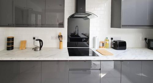 a kitchen with a white counter top with a sink at Spacious Semi - Off Street Parking - Central Crewe in Crewe