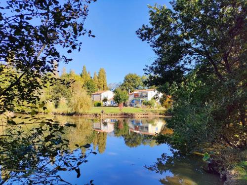 uitzicht op een meer met bomen en huizen bij Gîte Douceur de vivre in Saint-Avaugourd-des-Landes
