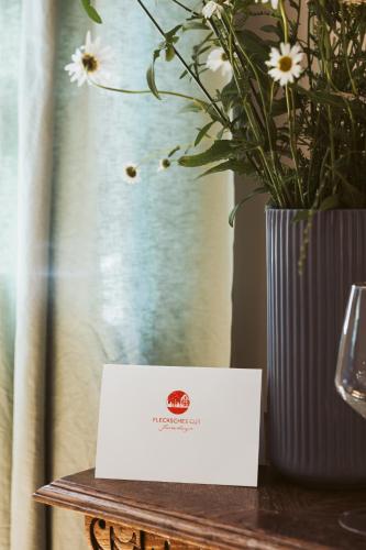 a white card on a table next to a vase with flowers at Flecksches Gut in Leipzig