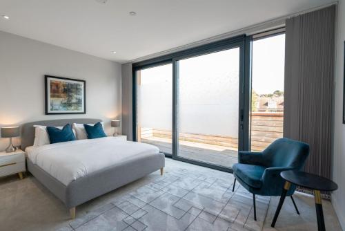 a bedroom with a bed and a chair and a large window at The Hampstead Hideout - Glamorous 3BDR Flat with Balcony in London