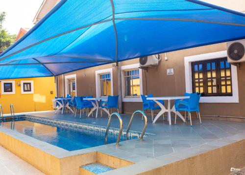 a pool with blue chairs and a table and a blue umbrella at Suru Express Hotel GRA in Ikeja