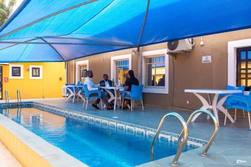 two people sitting at a table next to a swimming pool at Suru Express Hotel GRA in Ikeja