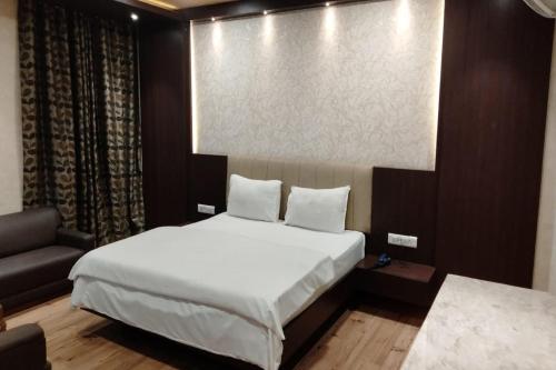 a bedroom with a white bed and a couch at Hotel Park Regency in Gorakhpur