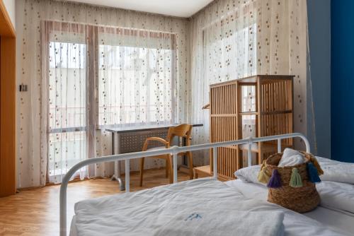 a bedroom with a bed and a desk and windows at Burov Apartment - artistic apartment in the heart of Varna suitable for up to 4 guests in Varna City