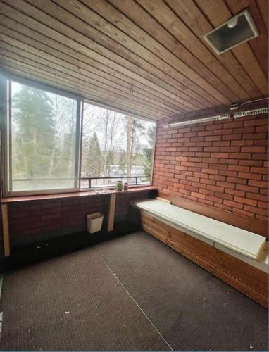 una habitación vacía con una pared de ladrillo y ventanas en Kotimaailma - Tilava rivitalo asunto 3MH ja sauna lähellä Korson keskustaa, en Helsinki