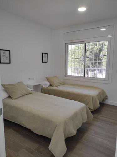Dos camas en una habitación blanca con ventana. en Apartamento Reformado con Aparcamiento. Playa 5min a pie., en Platja d'Aro