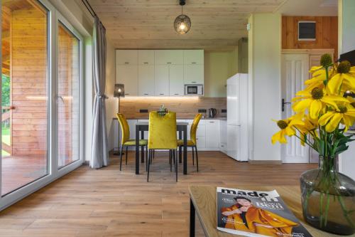 a kitchen and dining room with a table and yellow chairs at Rentynówka in Gietrzwałd