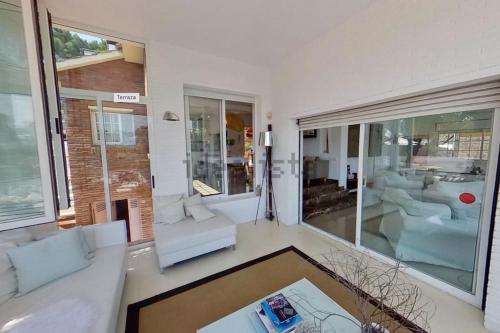 a living room with white furniture and large windows at Haidys House - Disfruta de las Vistas al mar in Castelldefels