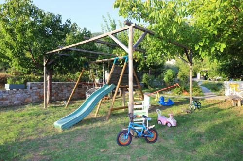 een speeltuin met een glijbaan en wat speelgoed in het gras bij Sklavos Studios in Neo Klima