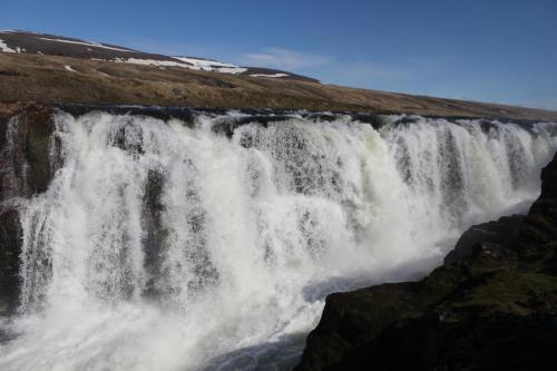 a waterfall on the side of a mountain at North West Restaurant & Guesthouse in Víðigerði