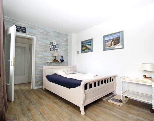 Schlafzimmer mit einem weißen Bett und Holzboden in der Unterkunft Beach Ole in Hörnum