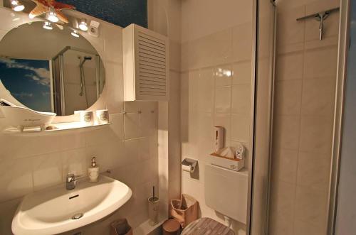 ein Bad mit einem Waschbecken, einem Spiegel und einer Dusche in der Unterkunft Beach Ole in Hörnum