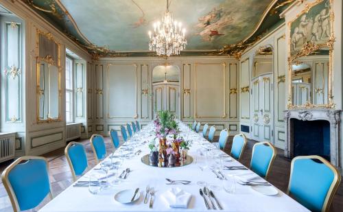 uma mesa longa numa sala com cadeiras azuis e um lustre em art'otel berlin mitte, Powered by Radisson Hotels em Berlim