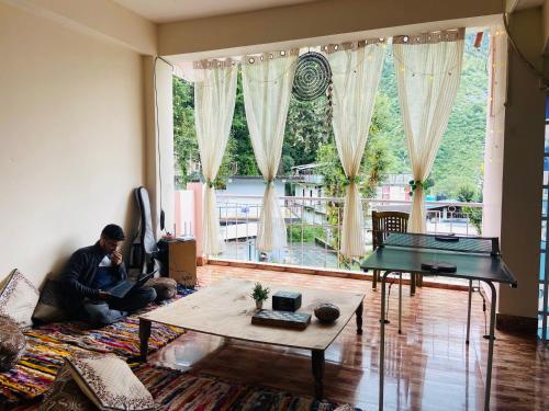 a man sitting on a couch in a living room at Rahgir Mcleodganj in McLeod Ganj