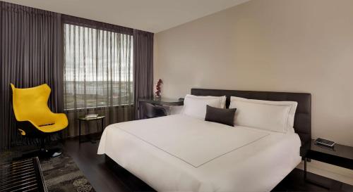 a bedroom with a white bed and a yellow guitar at Park Plaza London, Park Royal in London