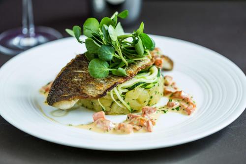 a white plate with a fish dish on a table at Park Plaza London, Park Royal in London