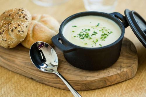 a bowl of soup on a wooden plate with a spoon at Park Plaza London, Park Royal in London