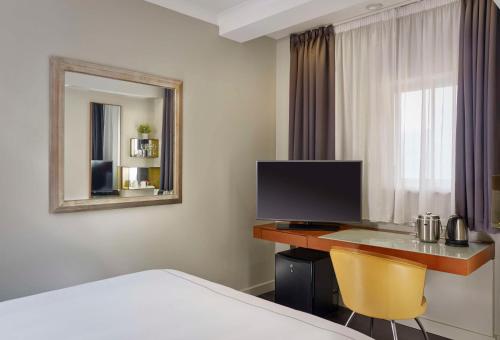 a hotel room with a desk with a television and a mirror at Park Plaza Nottingham in Nottingham