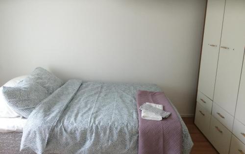 a bedroom with a bed with a gray blanket and a dresser at Sosa's villa. (Free Coffee, BBQ & Garden Fruits) in Turku