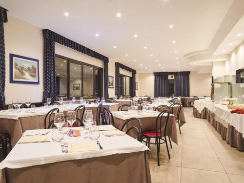 un comedor con mesas y sillas con manteles blancos en Hotel Polsa, en Brentonico
