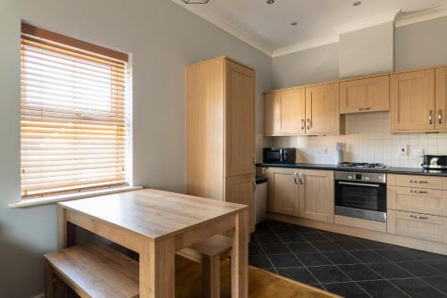 a kitchen with wooden cabinets and a wooden table at 2BR 2BA Apartment - Emperor Beds - Free Parking - Near LGW Airport in Crawley