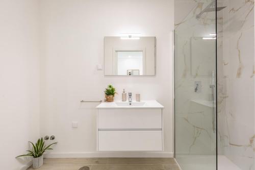 een witte badkamer met een wastafel en een douche bij Villa Patricia in Mariquiteira