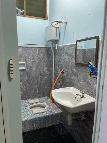 La salle de bains est pourvue d'un lavabo, de toilettes et d'un miroir. dans l'établissement ZZR Homestay, à Kampong Tanah Merah