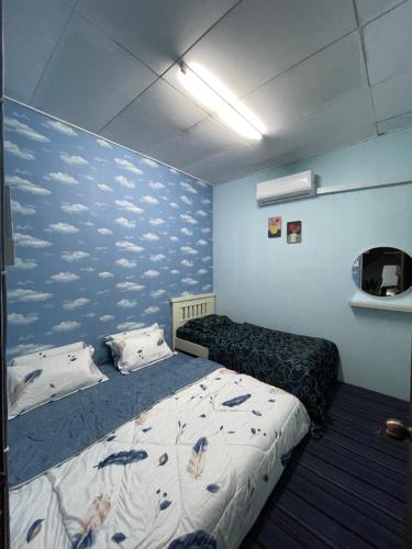 um quarto com uma cama e uma parede azul com nuvens em ZZR Homestay em Kampong Tanah Merah