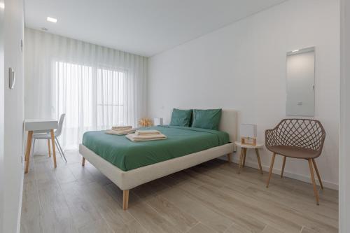 een slaapkamer met een bed met groene lakens en een stoel bij Villa Patricia in Mariquiteira