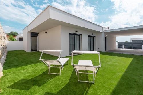 a lawn with two chairs and a table on it at Villa Patricia in Santa Barbara