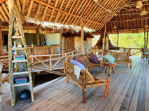 a room with a bed and chairs on a wooden floor at Mahali Maalum Barefoot Lodge in Mkwaja