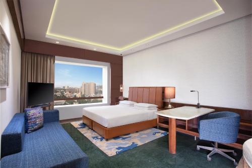 a bedroom with a bed and a desk and a window at Hyatt Regency Chennai in Chennai