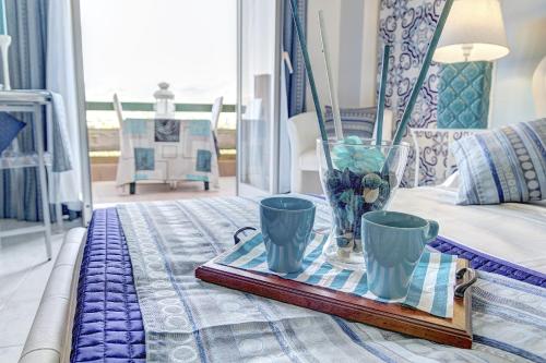 un vassoio con due tazze e un vaso su un letto di SuiteHome Taormina a Giardini Naxos