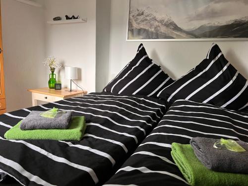 Una cama de rayas en blanco y negro con toallas verdes. en Gästehaus „Bei Emmi“, en Lichtenberg