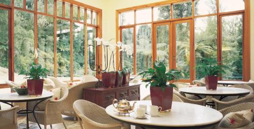 a room with tables and chairs and windows at Treetops Lodge & Estate in Horohoro