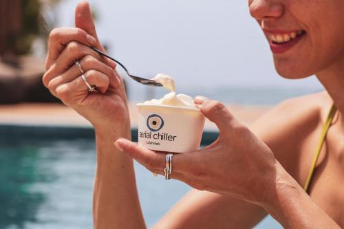 a woman eating a cup of coffee with a spoon at LalaGalu - Beachfront EcoCabins in Diani Beach