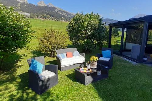 two chairs and a table in the grass at Studio dans un chalet avec jardin privatif in Leysin