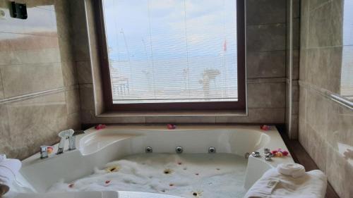 a bathroom with a dirty bath tub with a window at Focamor Otel in Yenifoça