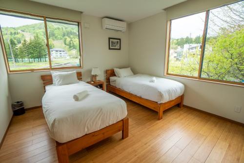 duas camas num quarto com duas janelas em Serenity Chalet, walk to the lifts Happoone Ski Resort em Hakuba