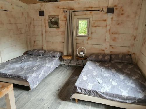 a bedroom with two beds in a log cabin at cabane in Aspremont
