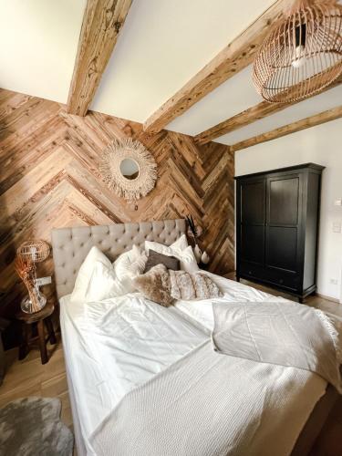 a bedroom with a white bed with a wooden wall at Bergzeit by Alpenidyll Apartments in Aich