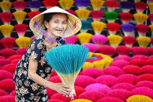 a woman in a straw hat holding a fan at Nguyên Khôi in Thôn Dương Xuân Hạ