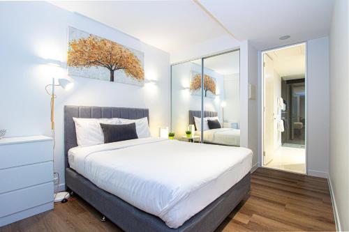 - une chambre avec un grand lit blanc et un miroir dans l'établissement Stay Like Home, à Melbourne