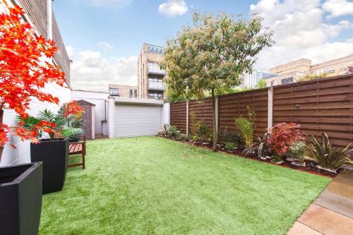 un patio trasero con césped verde y una valla en Central 4BDR home wgarden & parking en Londres