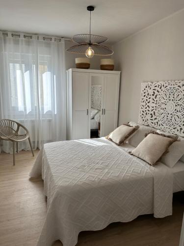 a white bedroom with a large bed and a chair at Nordic Home in Tudela