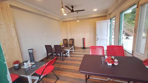 une salle à manger avec des chaises rouges, des tables et des fenêtres dans l'établissement FORTUNE HEIGHTS DALHOUSiE, à Dalhousie