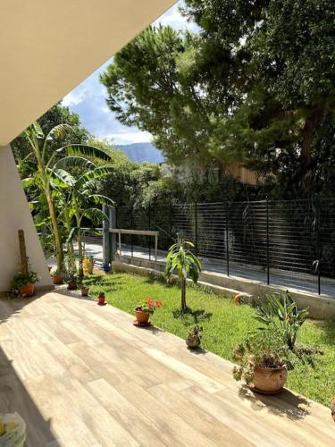 um jardim com vasos de plantas e um passadiço de madeira em Casa Woow em Carini