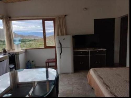 a kitchen with a refrigerator and a table in a room at Cabaña Abra del Monte Monohambiente in Cachí